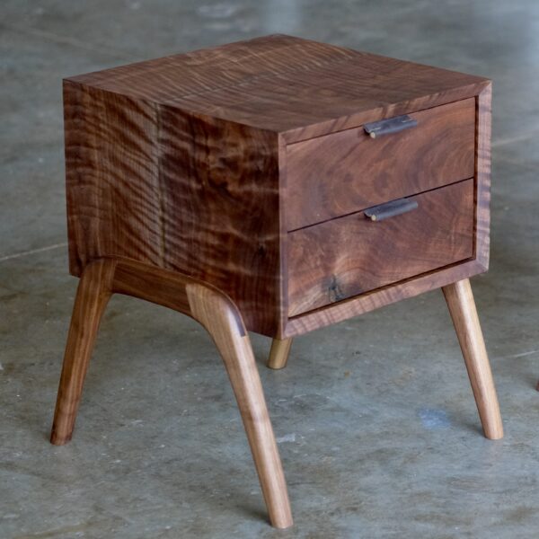 A two-drawer nightstand made of figured walnut with curved legs