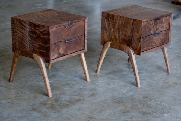 A set of walnut nightstands, each with two drawers and leather pulls.
