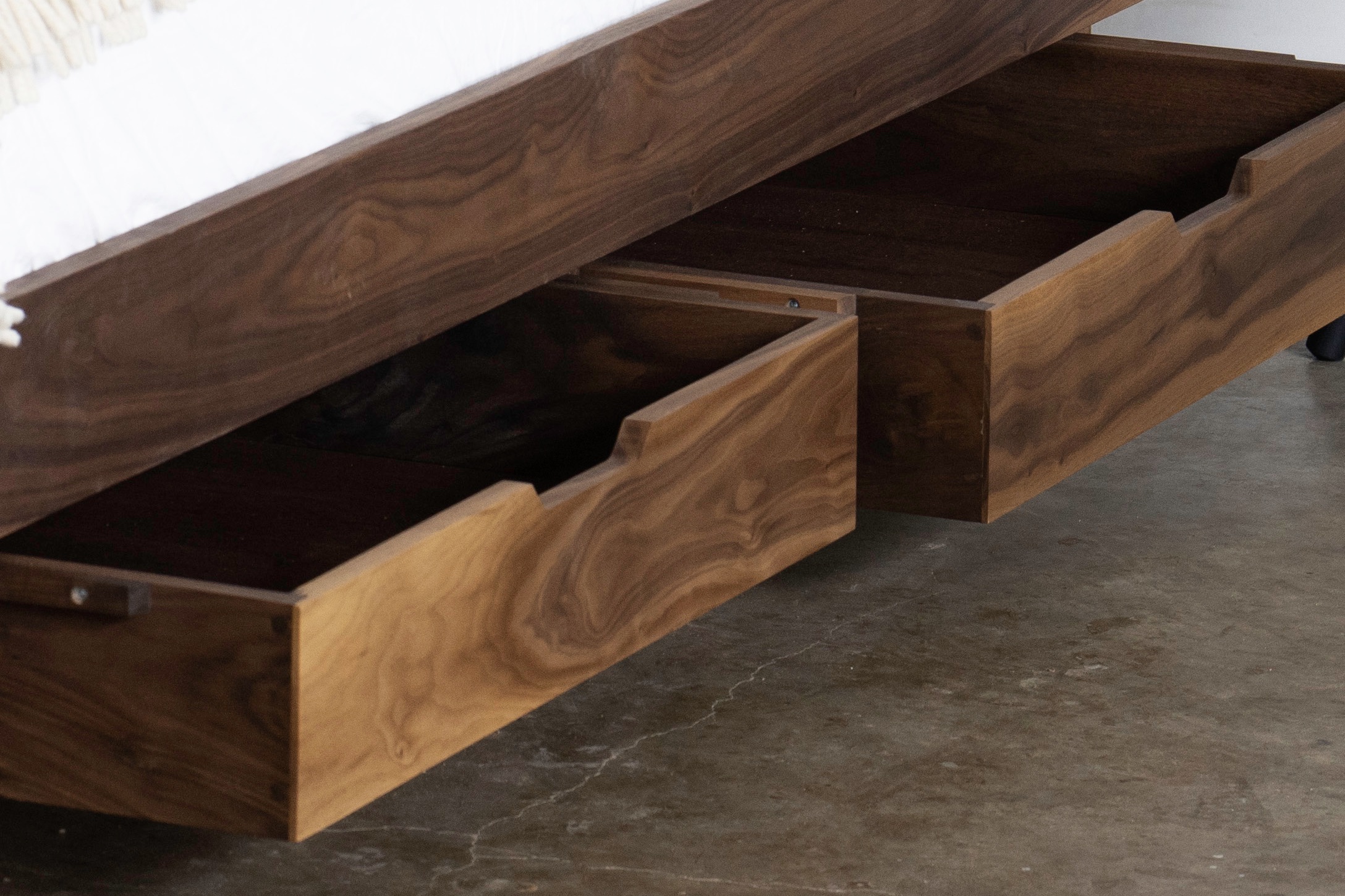 Two under-bed storage drawers with a notched cutout at the top of each. Made of walnut.