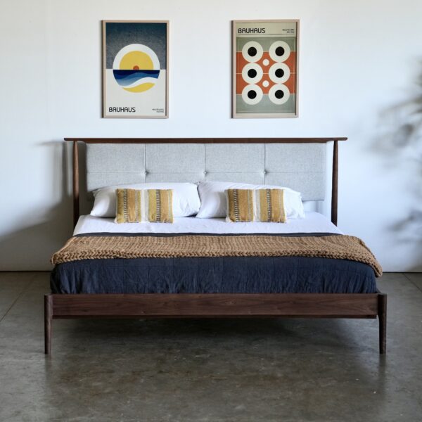 A walnut midcentury modern bed with an upholstered headboard that appears to float. The headboard is an oatmeal color.