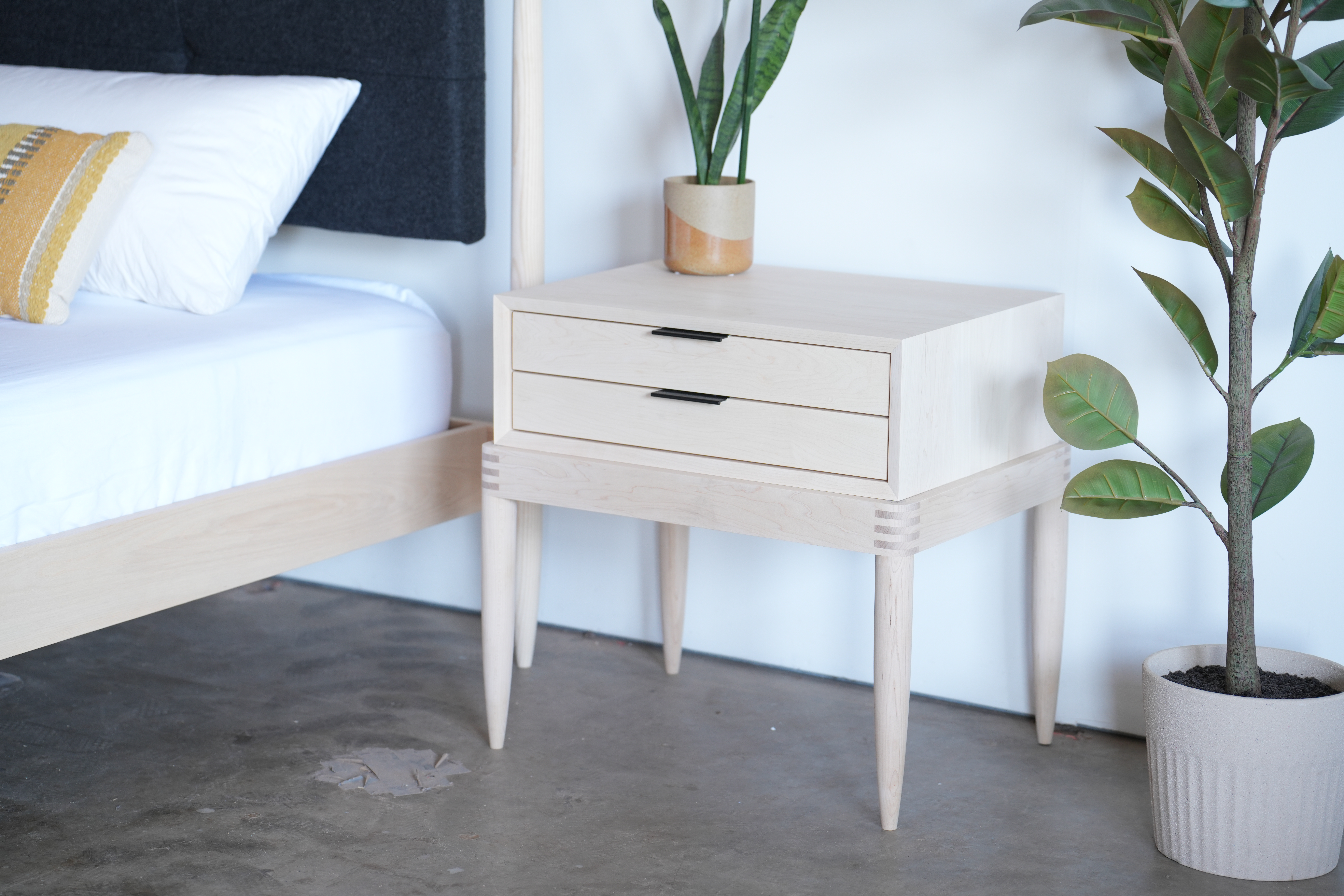 A maple nightstand with two drawers and black pulls.