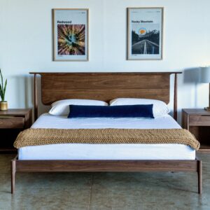 A midcentury modern bed made of solid walnut with a headboard that appears to float and two matching minimalist nightstands in walnut.