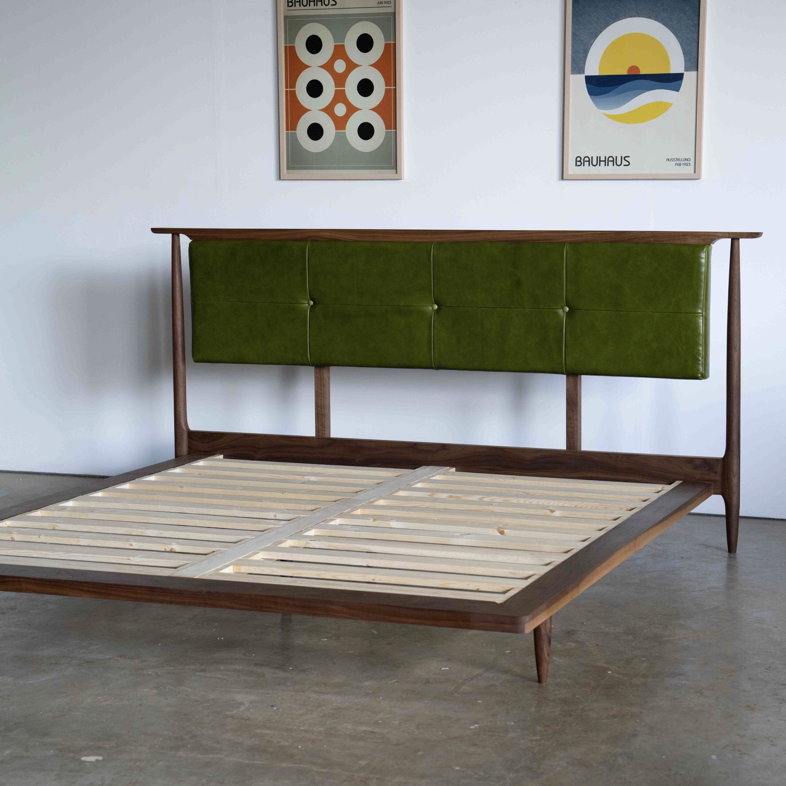 Scandinavian style walnut bed with upholstered green leather headboard.