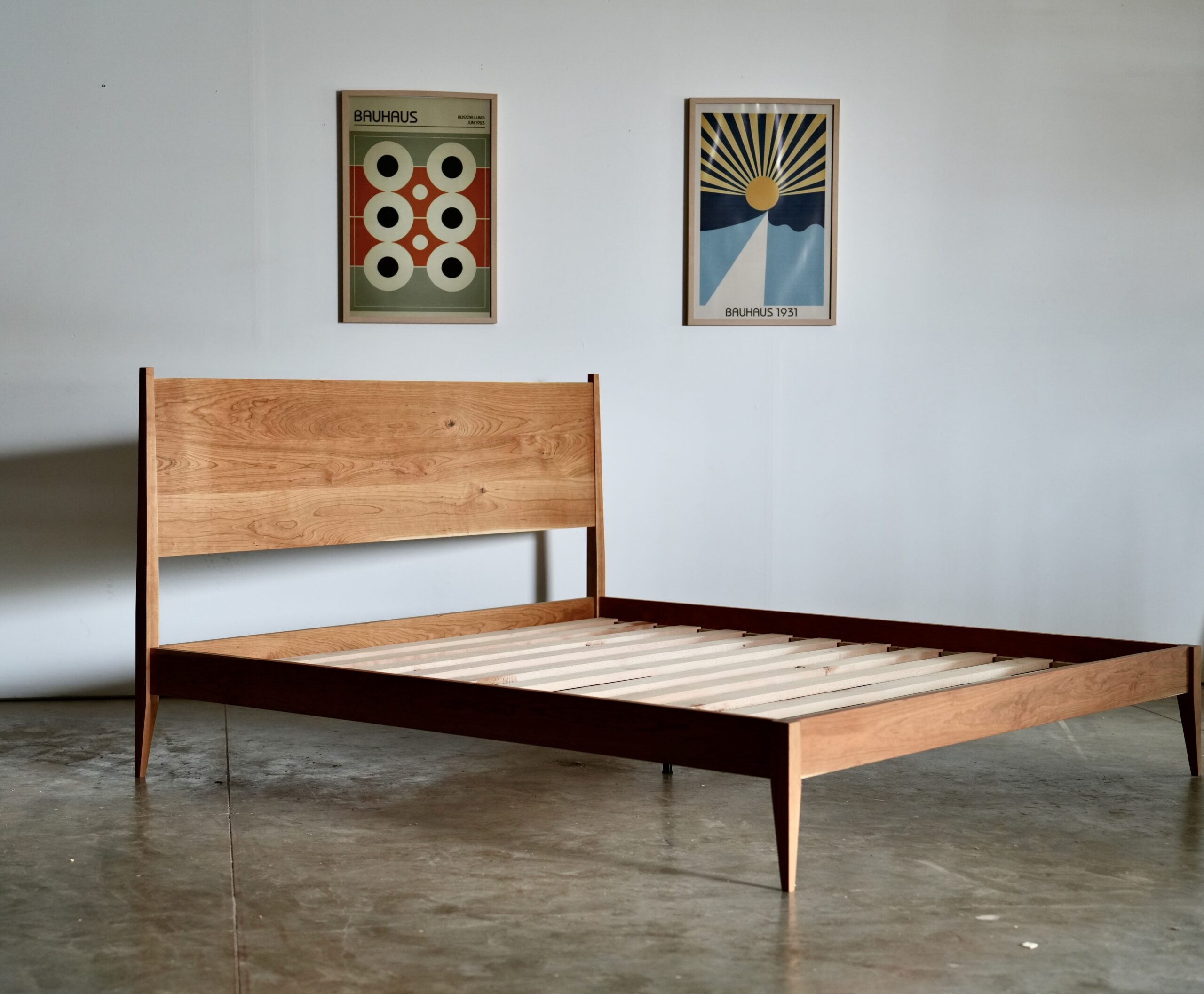 A cherry shaker style midcentury modern bed with tapered legs.