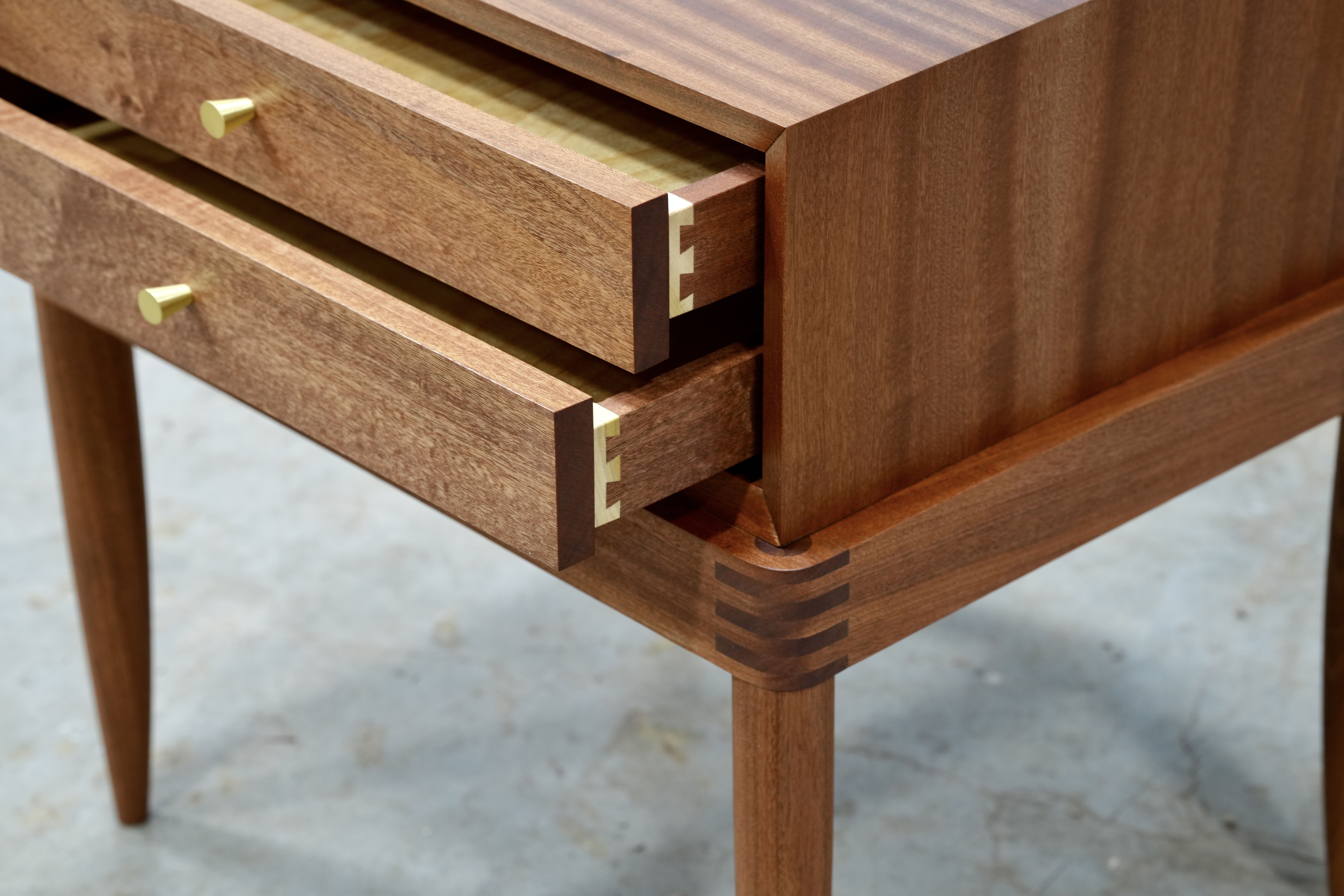A close-up of the finger joints and dovetails in a sapele nightstand