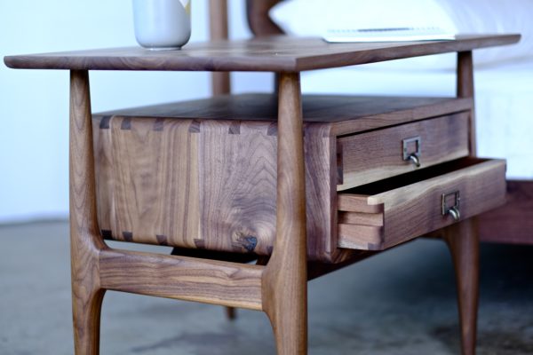A handmade side table that is Scandinavian style, with the drawers appearing to float under the table top and made of solid walnut.