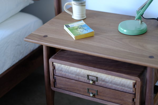 A handmade side table that is Scandinavian style, with the drawers appearing to float under the table top and made of solid walnut.