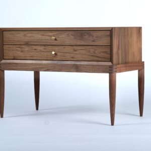 A simple two-drawer walnut nightstand with exposed joiner at the base and conical brass pulls.
