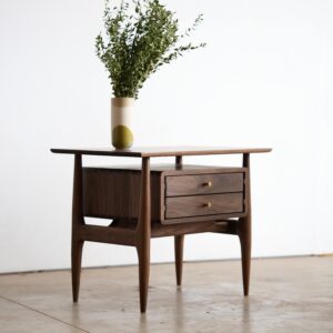A midcentury modern nightstand made of solid walnut with brass knobs